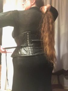 Miss R with a leather corset over the translucent black dress, still needing to be tightene